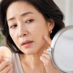 화장이 들뜬 볼과 입가를 거울로 확인하는 중년 여성
