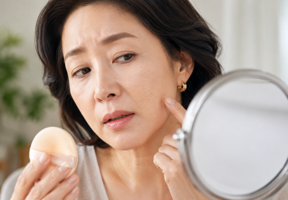 화장이 들뜬 볼과 입가를 거울로 확인하는 중년 여성