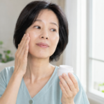 세안 후 볼의 피부 상태를 확인하며 보습크림을 든 50대 한국인 여성