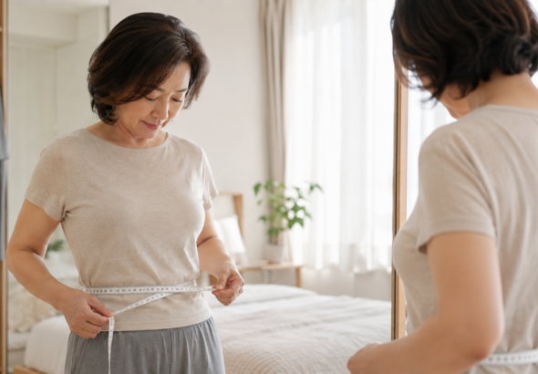 갱년기 뱃살 변화를 확인하기 위해 허리둘레를 측정하는 50대 여성